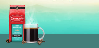 A bag of whole bean Community Coffee One-Hundred Percent Colombia medium-dark roast, next to a steaming coffee mug, on a two-tone green background.