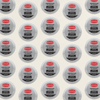 Rows of K-Cup lids for Community Coffee American Classic medium roast lie flat against a white background.
