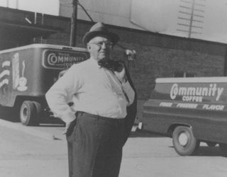 Community Coffee founder Cap Saurage poses in front of company delivery trucks.