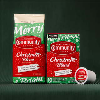 Packages of Community Coffee Christmas Blend medium roast sit on rolled-out green fabric.