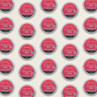 Rows of K-Cup lids for Community Coffee Cinnamon Roll flavored coffee lie flat against a white background.