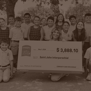 A woman and schoolchildren pose with a large Community Cash for Schools check, made out to Saint John Interparochial.