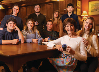 Third-generation Community Coffee owner Donna Saurage and her grandchildren pose together in a warmly lit kitchen.