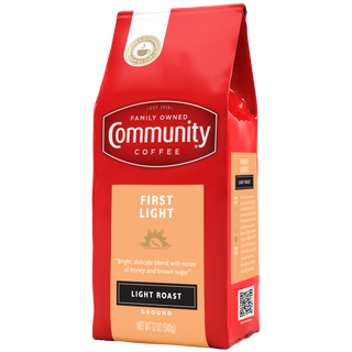 A twelve-ounce bag of ground Community Coffee First Light, light roast, rotated a quarter-turn to the left.