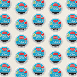 Rows of K-Cup lids for Community Coffee Grandma's Sugar Cookie flavored coffee lie flat against a white background.