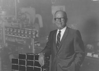 Second-generation Community Coffee owner HN Saurage stands next to coffee bags in the company's manufacturing plant.