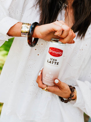 A person opening a Community Coffee Mocha Delight Iced Latte can.
