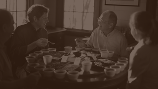 Members of the Saurage family hold spoons, while they test coffees around a circular table covered in cups and coffee beans.