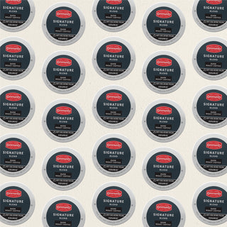 Rows of K-Cup lids for Community Coffee Signature Blend dark roast lie flat against a white background.