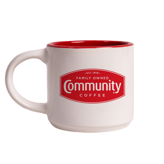 A white, 12-ounce coffee mug featuring the red Community Coffee bage logo, with the handle facing right.