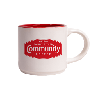 A white, 12-ounce coffee mug featuring the red Community Coffee bage logo, with the handle facing right.